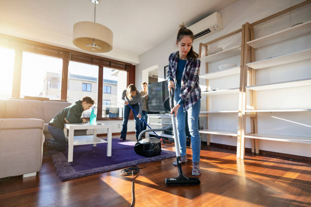A group of people using a vacuum to clean a room, showcasing teamwork in professional maid services.