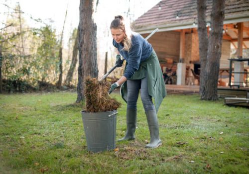 A woman collects grass using a bucket in a luxury vacation rental cleaning setting.